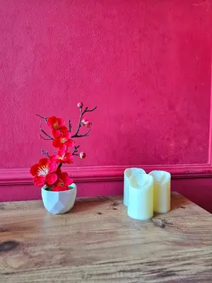 two candles and a vase with flowers on a table at Red Diamond in Niš