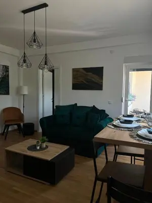 a living room with a green couch and a table at Aria Apartman Sokobanja in Soko Banja