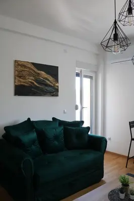 a living room with a green couch and a painting at Aria Apartman Sokobanja in Soko Banja