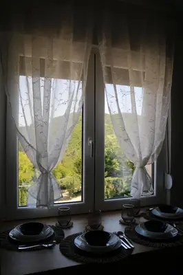 a table with two windows with plates and forks at Aria Apartman Sokobanja in Soko Banja