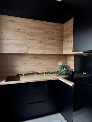 a kitchen with wooden cabinets and a black refrigerator at Aria Apartman Sokobanja in Soko Banja
