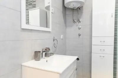 a white bathroom with a sink and a mirror at Viktor i Kasija green hill in Soko Banja