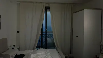a bedroom with a bed with white curtains and a balcony at Residence Hills Lux Hotels & Spa Kopaonik in Kopaonik