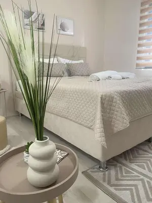 a bedroom with a bed and a table with a vase at Apartmani Safir Krusevac in Kruševac
