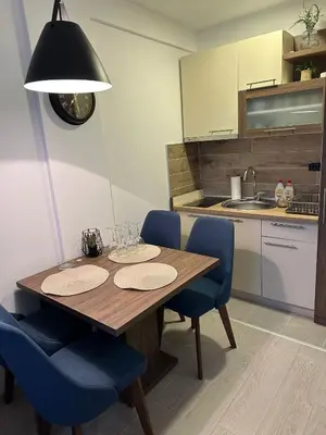 a kitchen with a wooden table and blue chairs at Emili N90a in Cajetina