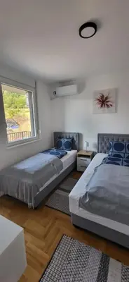 two beds in a bedroom with a window at Apartman Iznad Sunca in Soko Banja