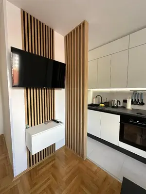 a kitchen with white cabinets and a flat screen tv at Apartman Iznad Sunca in Soko Banja