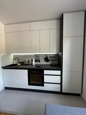 a kitchen with white cabinets and a black counter top at Apartman Iznad Sunca in Soko Banja