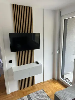 a living room with a flat screen tv on a wall at Apartman Iznad Sunca in Soko Banja