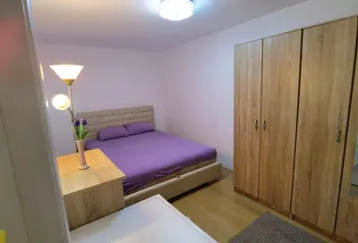 a small bedroom with a purple bed and a cabinet at Apartman Emilija i Julija in Soko Banja