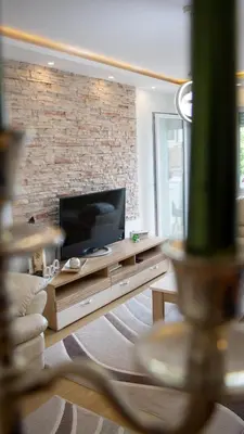 a living room with a television and a brick wall at Apartman Emilija i Julija in Soko Banja