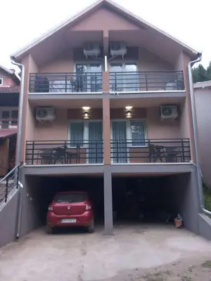 a red car parked in a garage in front of a building at Smeštaj Gligorijević in Lukovo