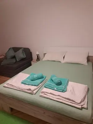 a bed with towels on top of it with a couch at Vila RUŽA - House of Roses in Soko Banja
