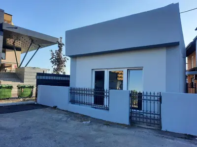 a white house with a fence in front of it at Apartman Maja in Leskovac