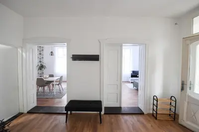 a living room with white walls and a black ottoman at Family House in Leskovac
