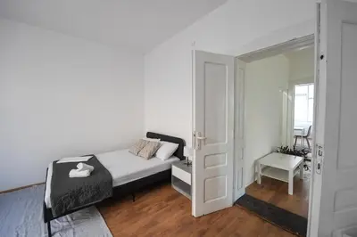 a white bedroom with a bed and a table at Family House in Leskovac