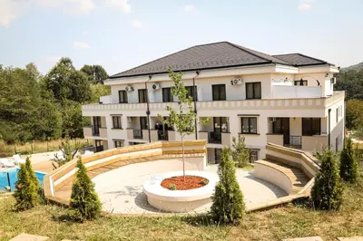 a large white building with a pool in front of it at Grey Apartment On the Hill in Vrnjačka Banja