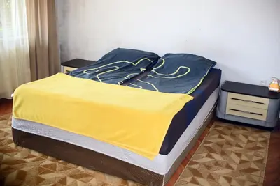 a bed with a yellow blanket on top of it at Apartman LUX*** in Leskovac