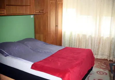 a bed with a red blanket and a window at Apartman LUX*** in Leskovac