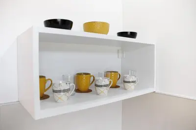 a white shelf with cups and bowls on it at Vila Jevtić studio 3 in Soko Banja