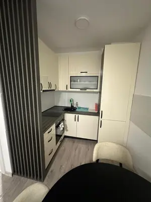 a small kitchen with white cabinets and a table and chairs at Lacky-ca in Prokuplje