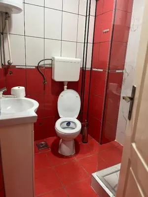 a red and white bathroom with a toilet and a sink at Royal suite Nis in Niš