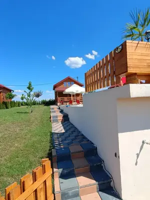 a walkway next to a white wall with a fence at Vikendica sa bazenom Čarolija Kruševac in Kruševac