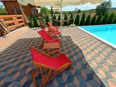 three chairs and an umbrella next to a swimming pool at Vikendica sa bazenom Čarolija Kruševac in Kruševac