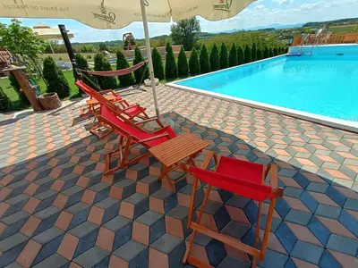 two chairs and an umbrella next to a swimming pool at Vikendica sa bazenom Čarolija Kruševac in Kruševac