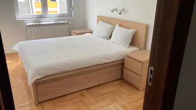 a bed with white sheets and pillows in a room at Apartman Grey LUX in Pirot