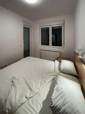 a bedroom with two large white beds and two windows at Apartman Grey LUX in Pirot