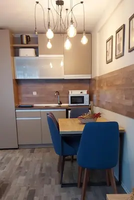a kitchen with a wooden table and blue chairs at Apartman Viva Milmari in Kopaonik