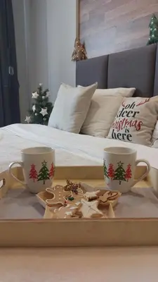 a tray with two cups and cookies on a bed at Apartman Viva Milmari in Kopaonik