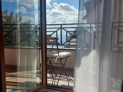 a chair sitting on a balcony looking out a window at Apartman Viva Milmari in Kopaonik