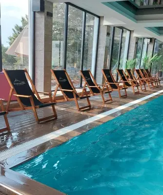 a row of lounge chairs next to a swimming pool at Apartman Viva Milmari in Kopaonik