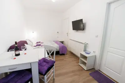 a room with a bed and a table with purple chairs at Vila Jevtić studio 1 in Soko Banja