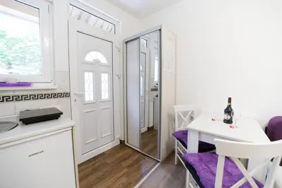 a white kitchen with a white table and purple chairs at Vila Jevtić studio 1 in Soko Banja