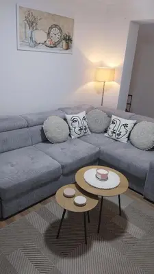 a living room with a blue couch and two tables at Apartman Kraljice Natalije in Vrnjačka Banja