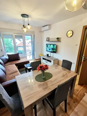 a living room with a wooden table with flowers on it at Trajkovic One Bedroom Apartment in Soko Banja