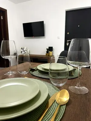 a wooden table with plates and wine glasses on it at Millie's apartments in Ćuprija