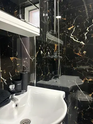 a bathroom with a white sink and a black wall at Millie's apartments in Ćuprija