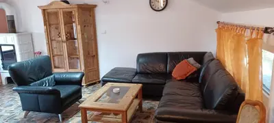a living room with a black leather couch and a chair at Vikendica Sofia in Žagubica