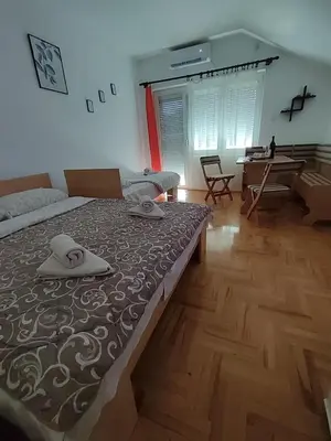 a bedroom with a large bed and a wooden floor at Latinski apartman in Soko Banja