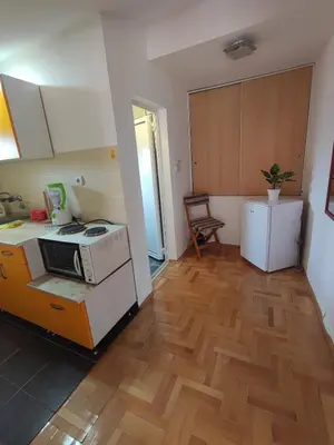 a kitchen with a stove and a wooden floor at Latinski apartman in Soko Banja