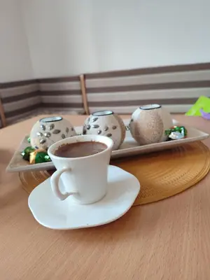 a cup of coffee on a table with a plate of cookies at Latinski apartman in Soko Banja