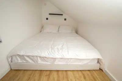 a white bed in a small room with a wooden floor at Vila Dolina Mira in Zabrega