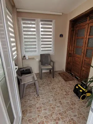 a room with a chair and a table and windows at Apartman Meridian in Zaječar