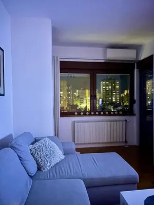 a living room with a blue couch in front of a window at PLANIS apartments in Niš
