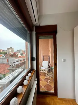 a balcony with a view of a chair and a window at PLANIS apartments in Niš