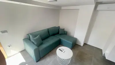 a living room with a green couch and a table at Amigos Suits in Niš